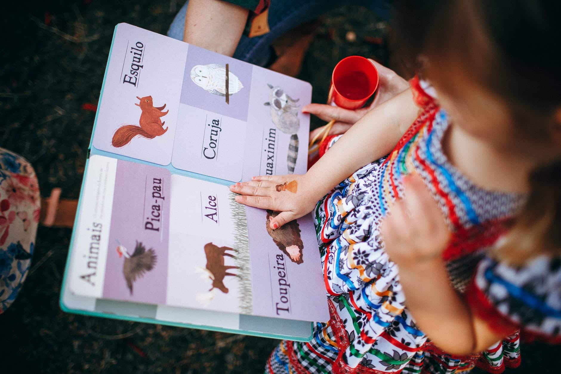 child reading book with mother in garden